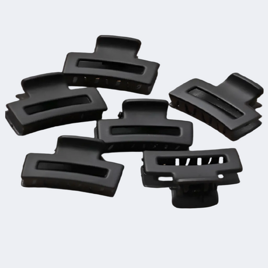 Set of black hair clips on a brown background with a ruler for scale.