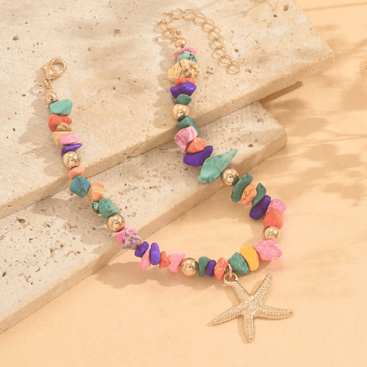 Colorful beaded bracelet with a starfish charm on a sandy background