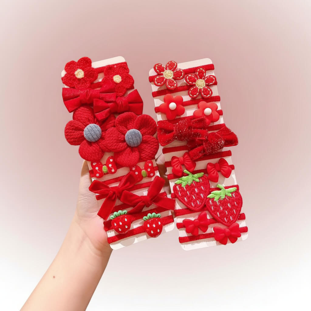 Set of red floral and bow hair accessories held by a hand on a white background