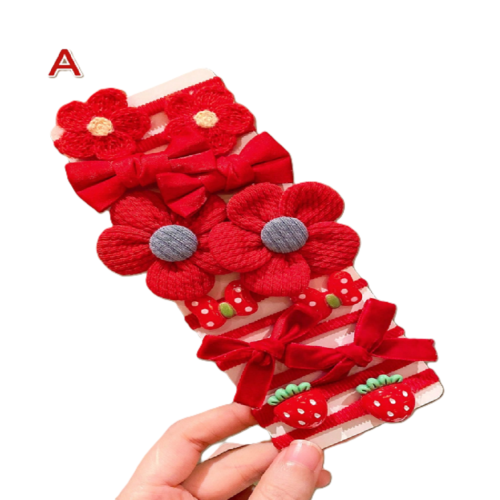 Set of red floral and bow hair accessories held by a hand on a white background
