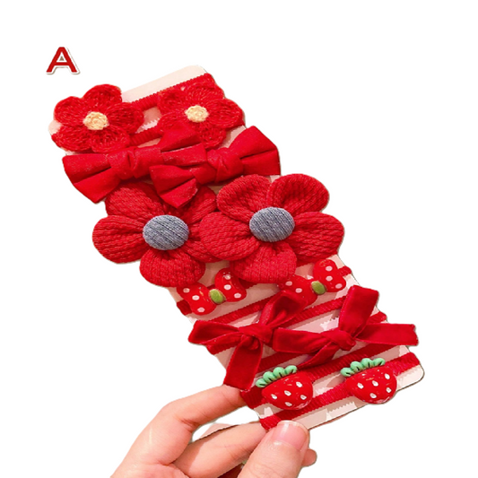 Set of red floral and bow hair accessories held by a hand on a white background