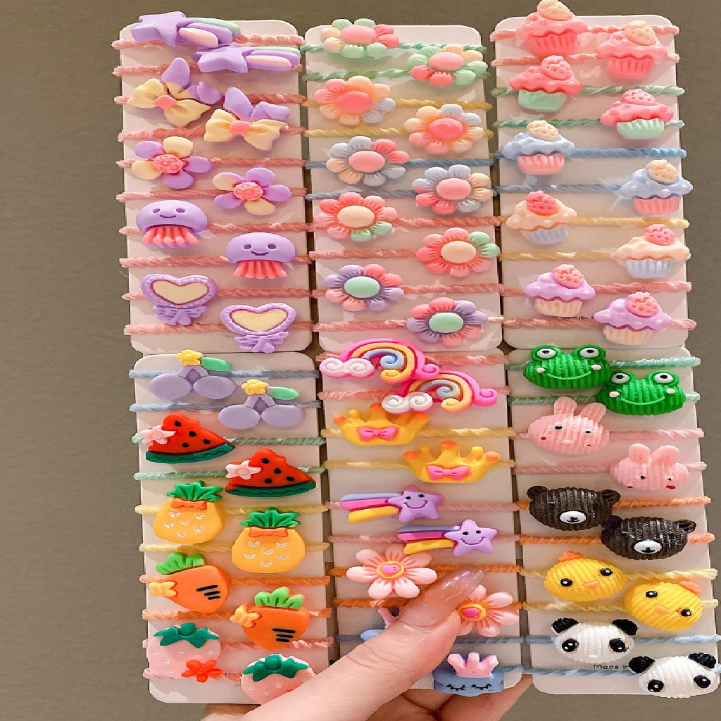 Collection of colorful hair clips held by a hand against a brown background