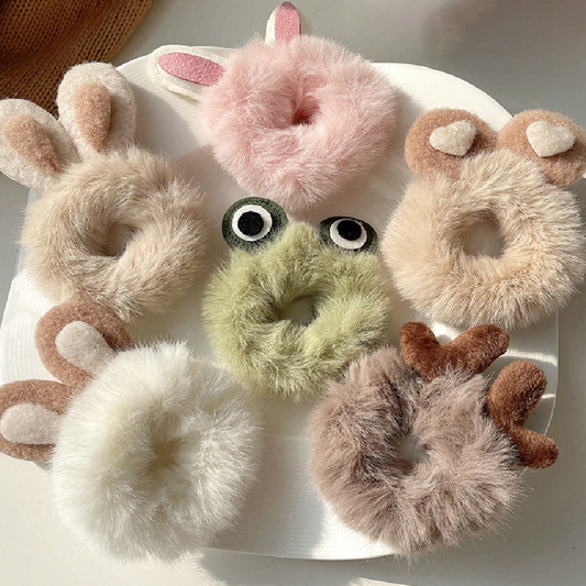Set of fluffy animal-themed hair ties on a white plate