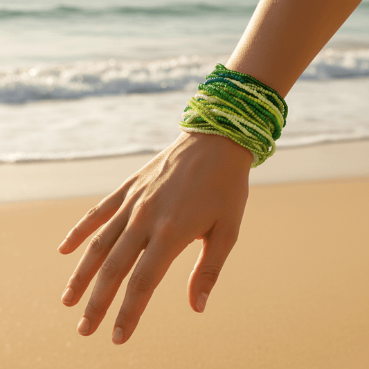 Hand wearing a green bracelet with a beach background