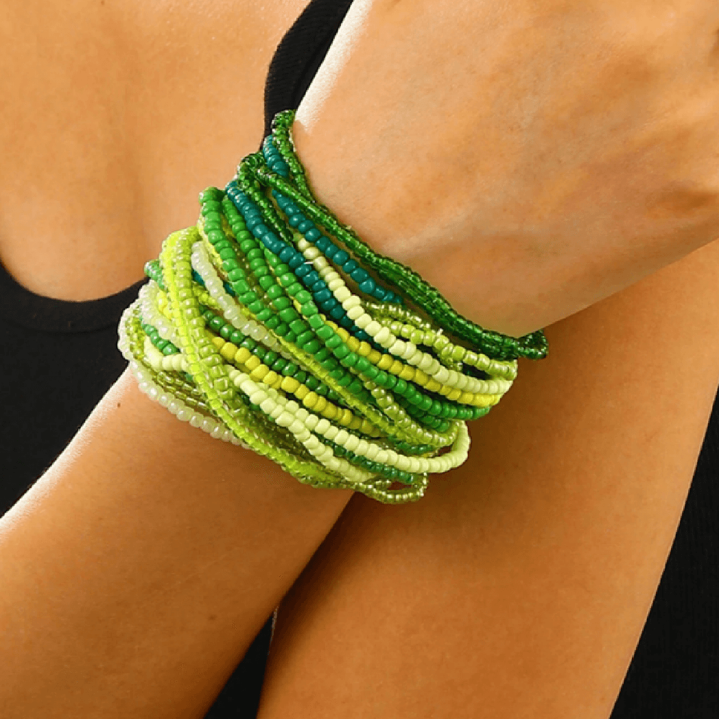 Green beaded bracelet on a wrist with a blurred background