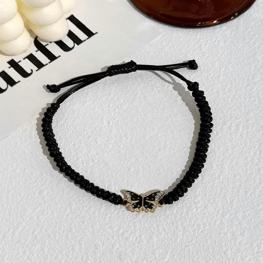 Black beaded bracelet with a butterfly charm on a light gray surface.