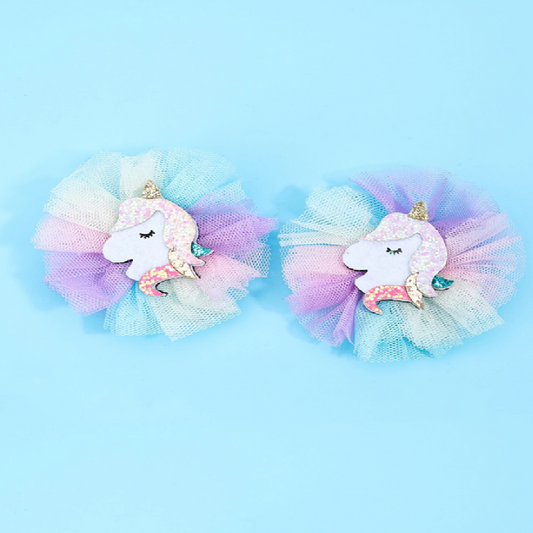 Two colorful unicorn hair accessories with tulle on a light blue background