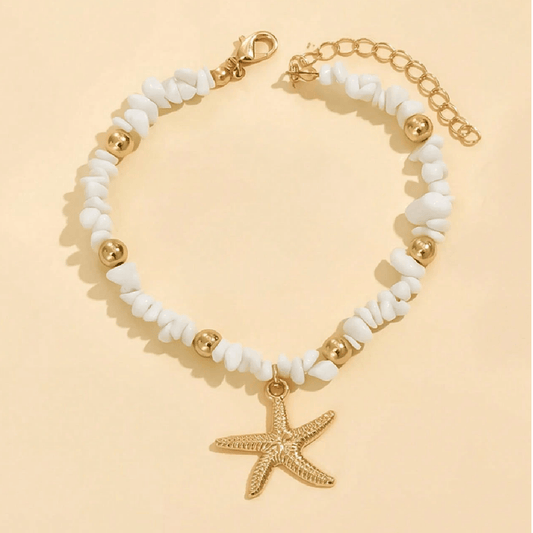 Bracelet with white beads and gold starfish charm on a beige background