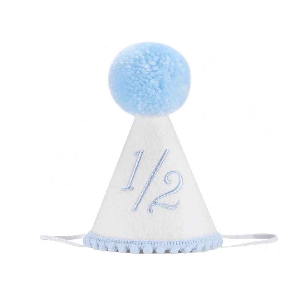 A white half birthday party hat with a light blue pom-pom on top, featuring the text '1/2' embroidered on the front and a light blue pom-pom trim along the brim.