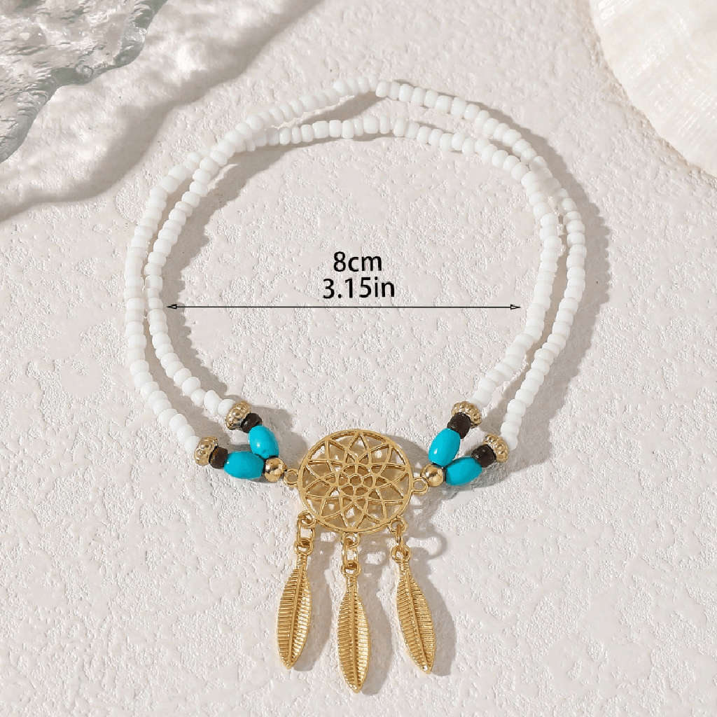 White beaded dreamcatcher necklace with gold-toned metal accents, turquoise beads, and hanging feather charms, shown on a light textured background with a measurement overlay indicating 8cm (3.15in) width.