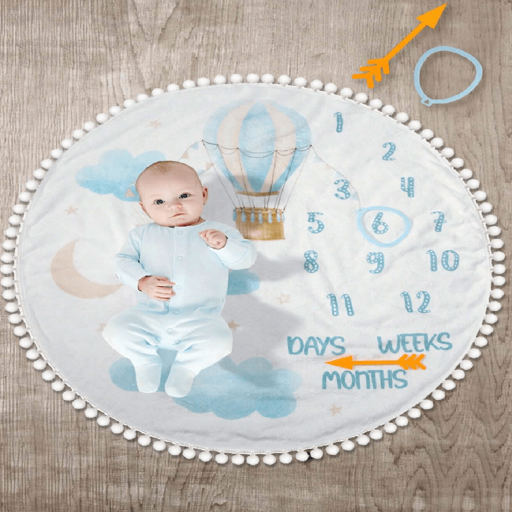 Baby milestone blanket with hot air balloon design and baby photo on a wooden surface
