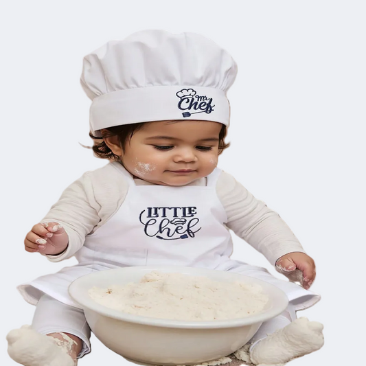 Baby wearing a 'Little Chef' apron and hat with flour on a white background