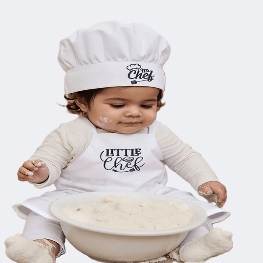 White chef hat and apron with 'Little Chef' text on a beige surface.