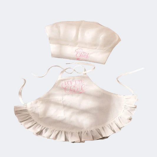 White chef hat and apron set with 'Little Chef' text on a gray textured background
