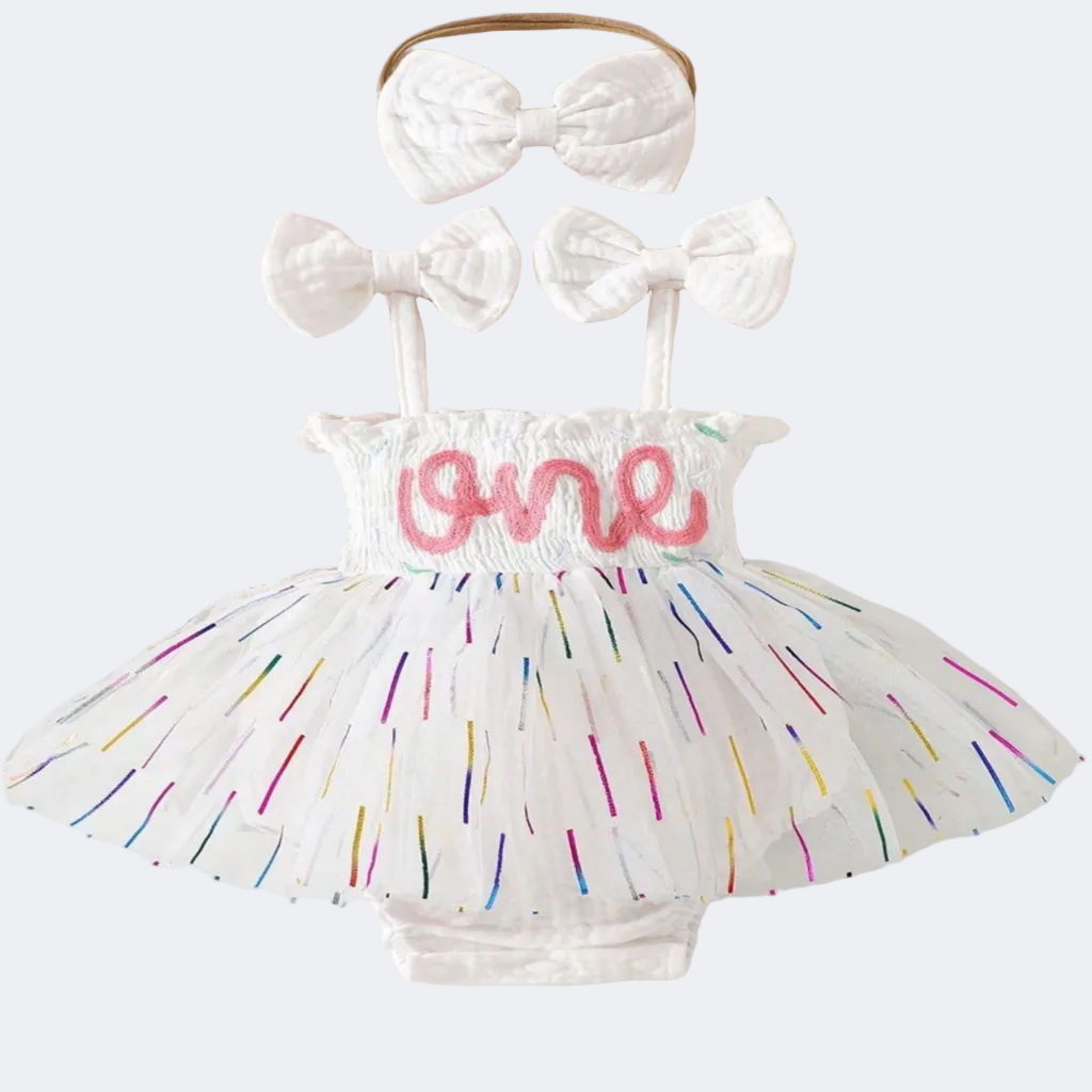 Baby outfit with colorful tutu, white bows, and 'one' lettering on a lace background.