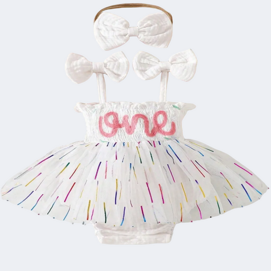 Baby outfit with colorful tutu, white bows, and 'one' lettering on a lace background.
