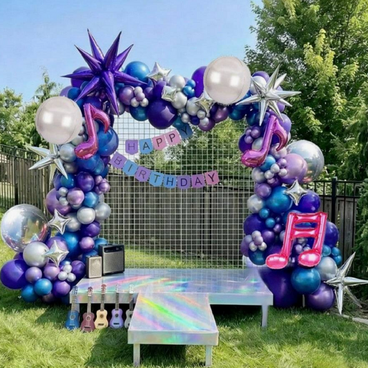 Colorful balloon arch with 'Happy Birthday' banner in a backyard setting
